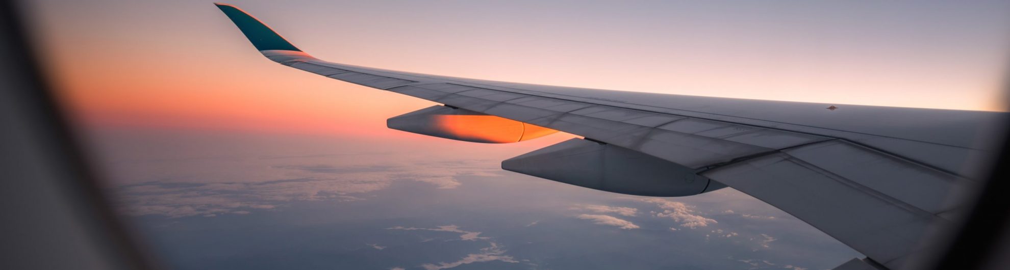 Silhouette wing of an airplane at sunrise view through the window.